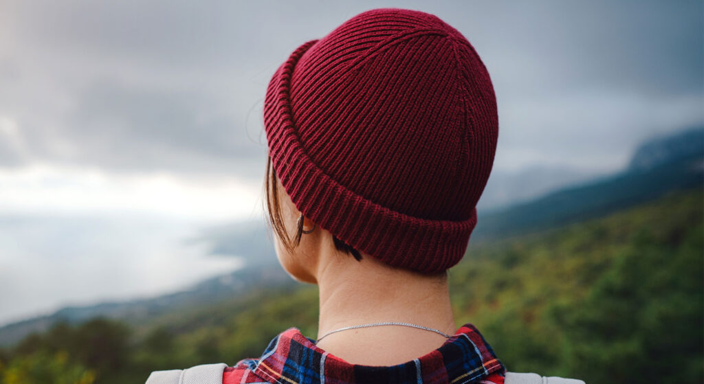 An inspiring young woman in recovery confidently stands at the summit of a majestic mountain, reflecting on her remarkable journey.